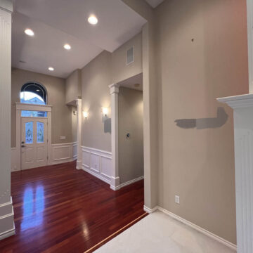 An empty room with hardwood floors, white trim, a fireplace, and arched windows after an interior painting project in Tigard that brightened the space.