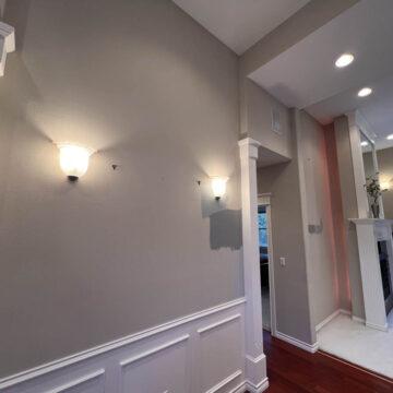 Interior view of a room with wall sconces, wainscoting, and hardwood floors following an interior painting project in Tigard that brightened the space.