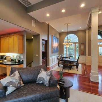 Open-concept living space with a kitchen, dining area, and living room, featuring hardwood floors and modern decor. An interior painting project in Tigard brightened the space.