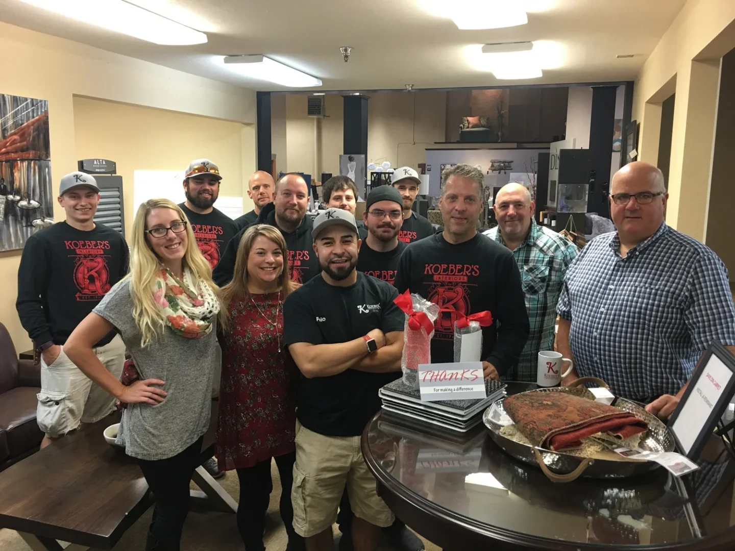 People in "Koerbers" shirts gather indoors with food and gifts, celebrating as recommended Portland painting contractors Pearl Painters.