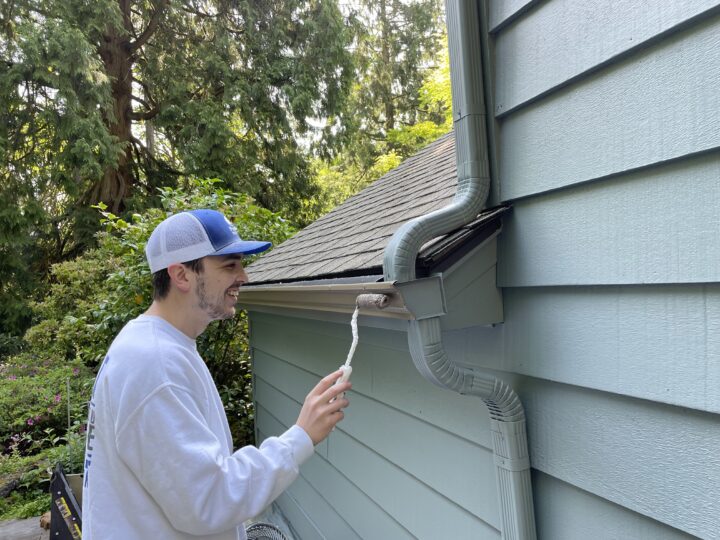 A man performing an exterior paint job on a house in Summer 2023.