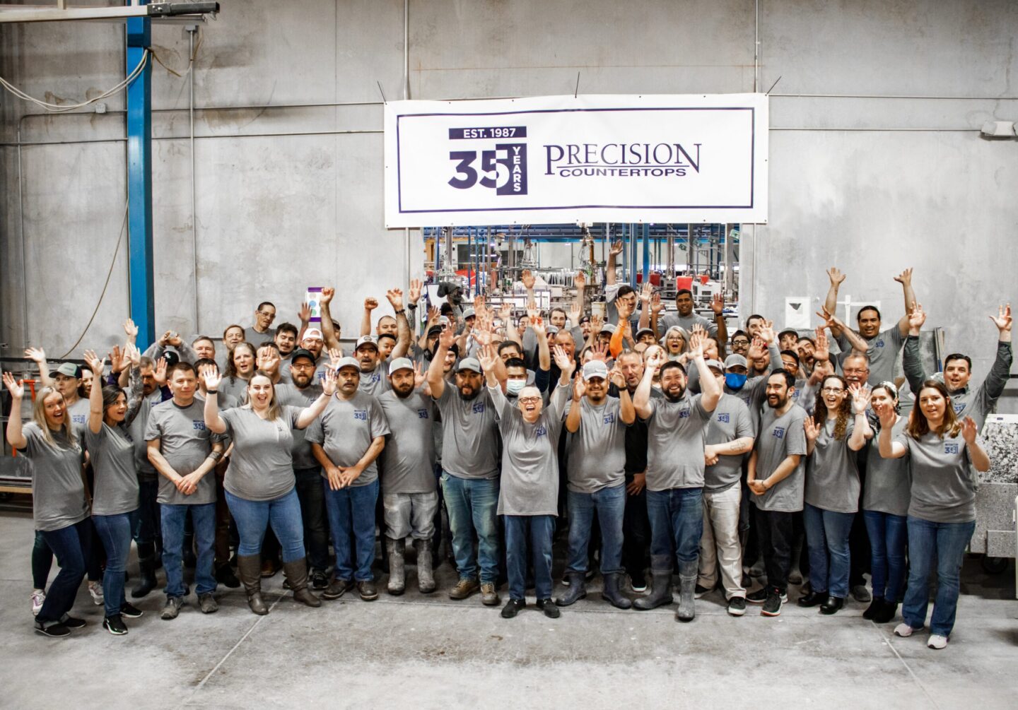 A group in gray shirts poses under a "35 Years Precision Countertops" banner; Portland painter Pearl Painters not shown.