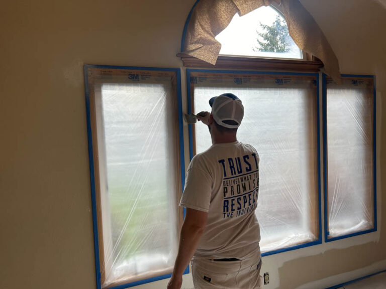 A man painting an interior window in a Beaverton home.