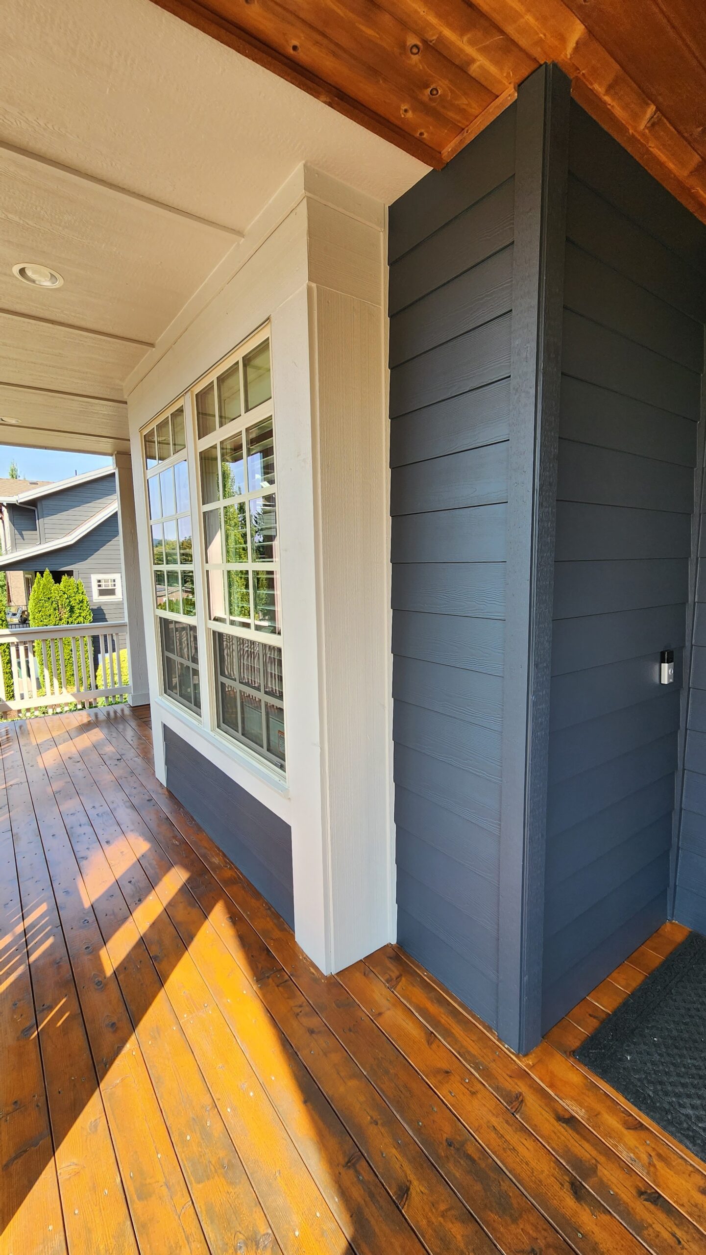 The front porch of a home with fresh blue siding and wood flooring.