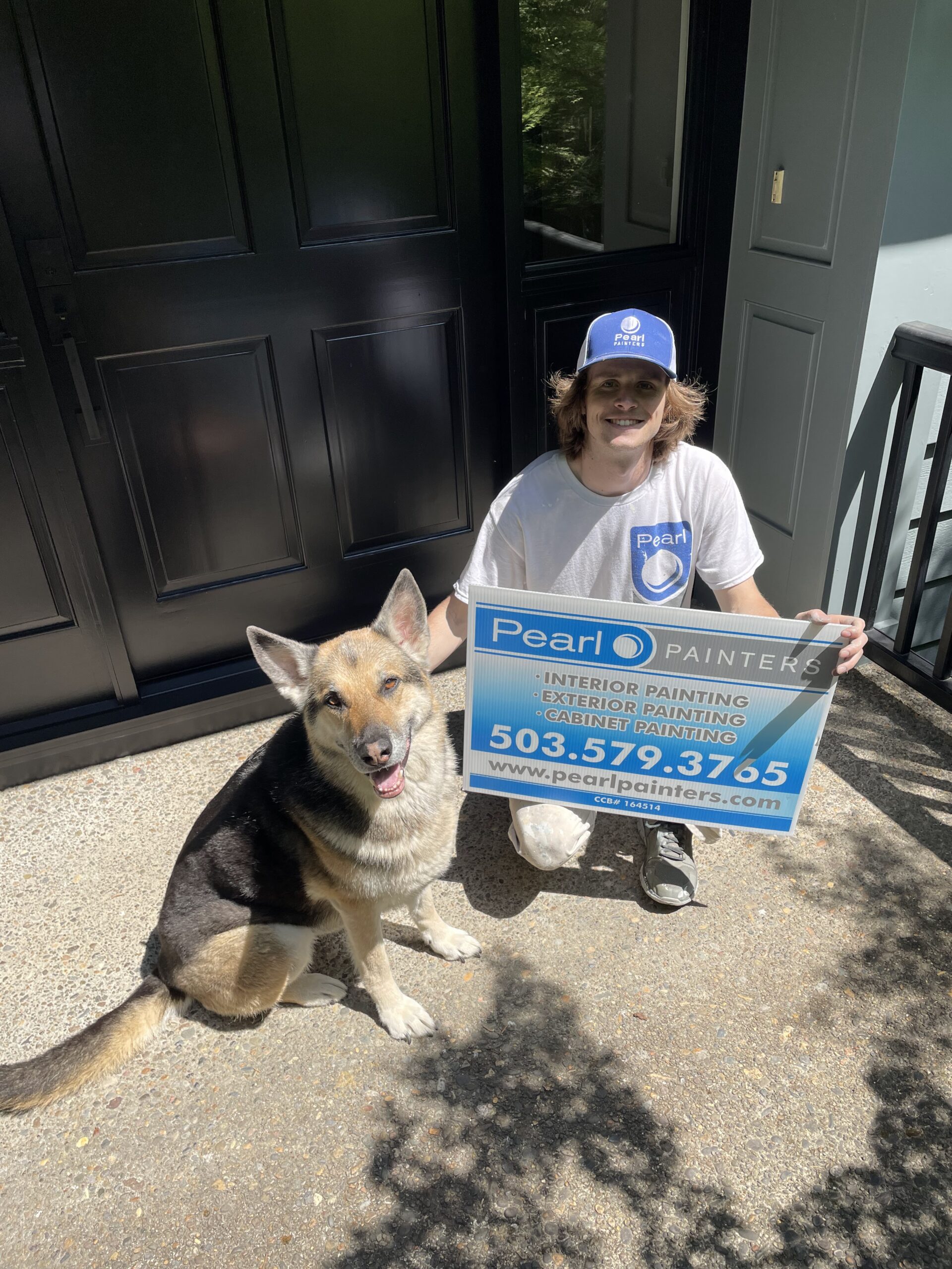 A man with a dog holding a sign promoting Exterior Paint for Summer 2023.