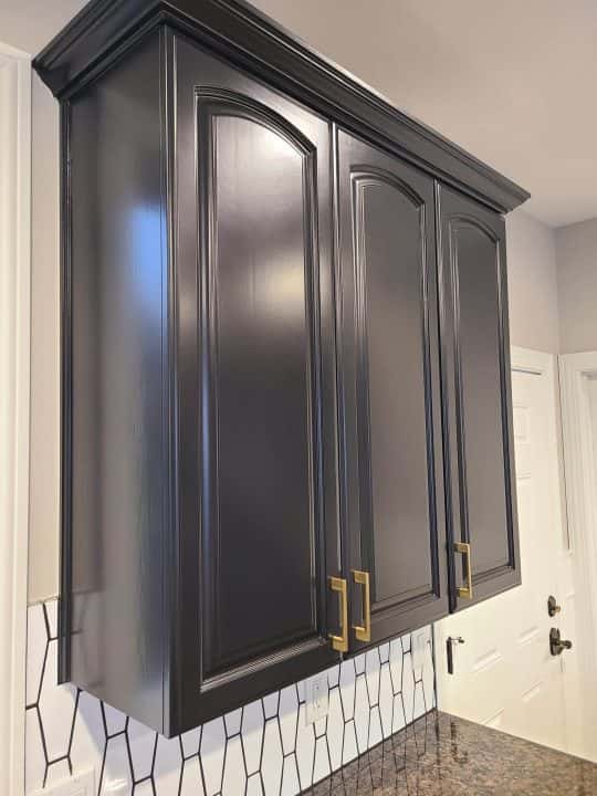A modern makeover for a kitchen in Tigard featuring black cabinets with gold hardware.