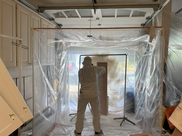 A man in a protective suit is cabinet painting in a Portland kitchen.