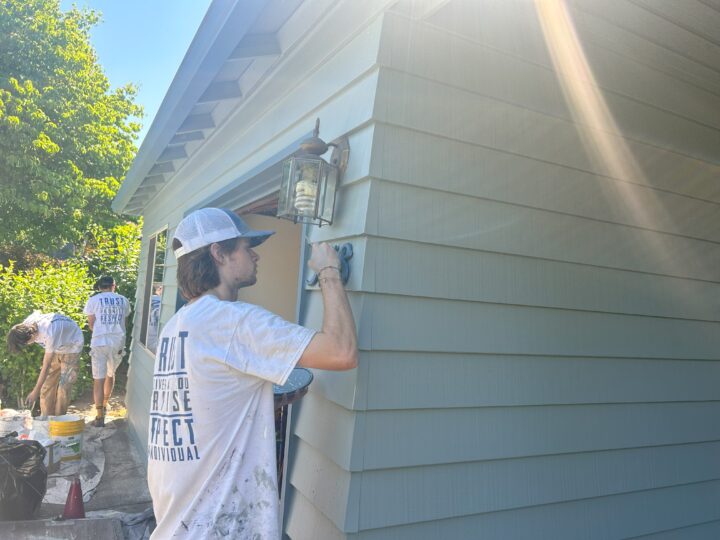 A trustworthy man painting the siding of a house in Portland, bringing about a remarkable home transformation.