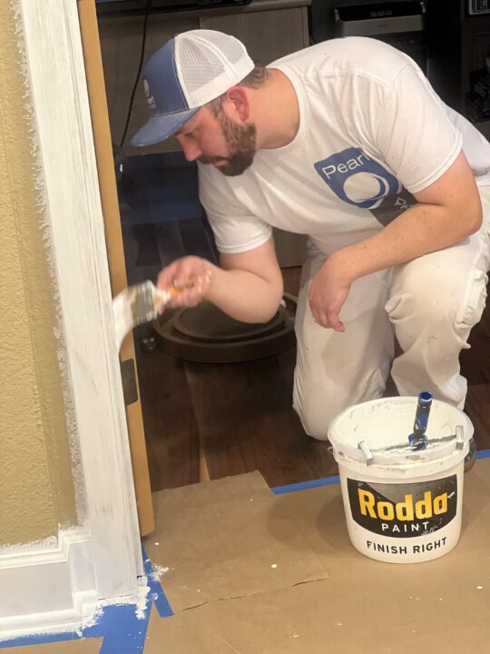 Painter painting trim inside home.