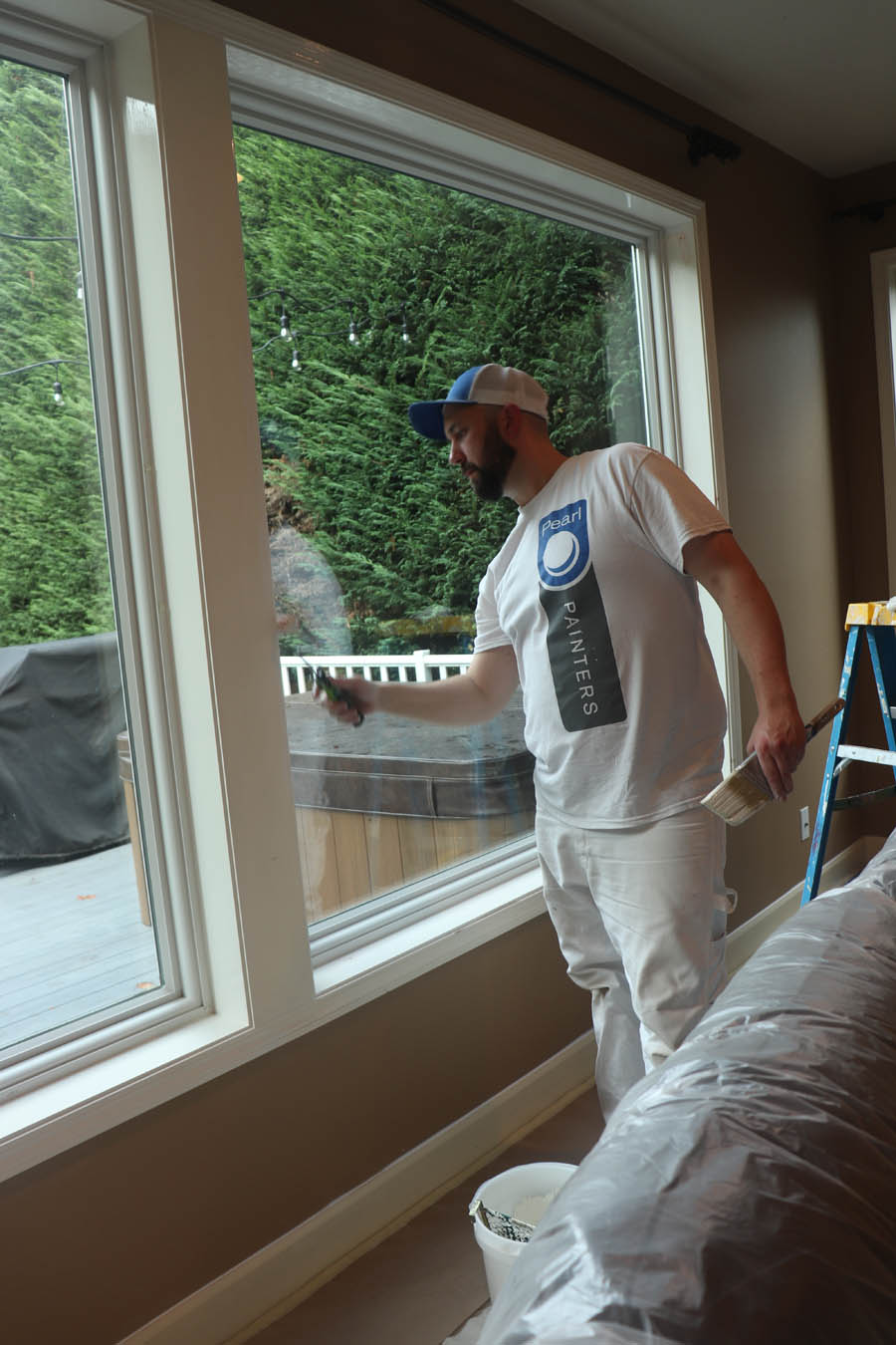 Painter carefully working on paint around window inside Tigard home