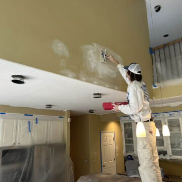A man painting a ceiling in a Wilsonville home with high ceilings.