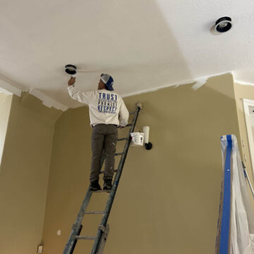 A man in Wilsonville painting the ceiling of a home.