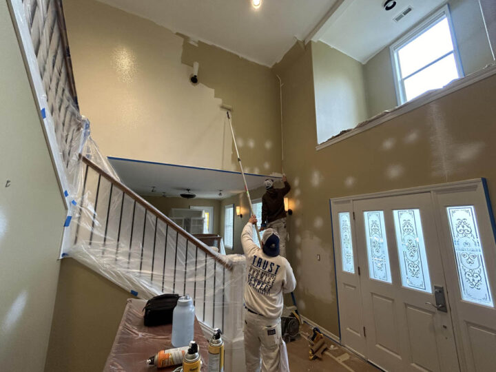 A man painting a staircase in a Wilsonville home with high ceilings.