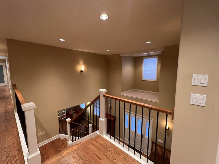 A stairway leading to a basement in a home with high ceilings.