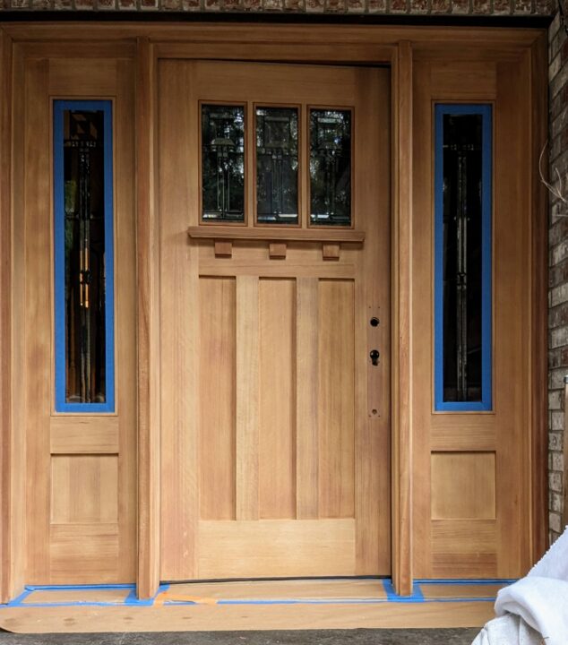 Wooden front doors with sidelights taped for painting by Pearl Painters in the PNW.
