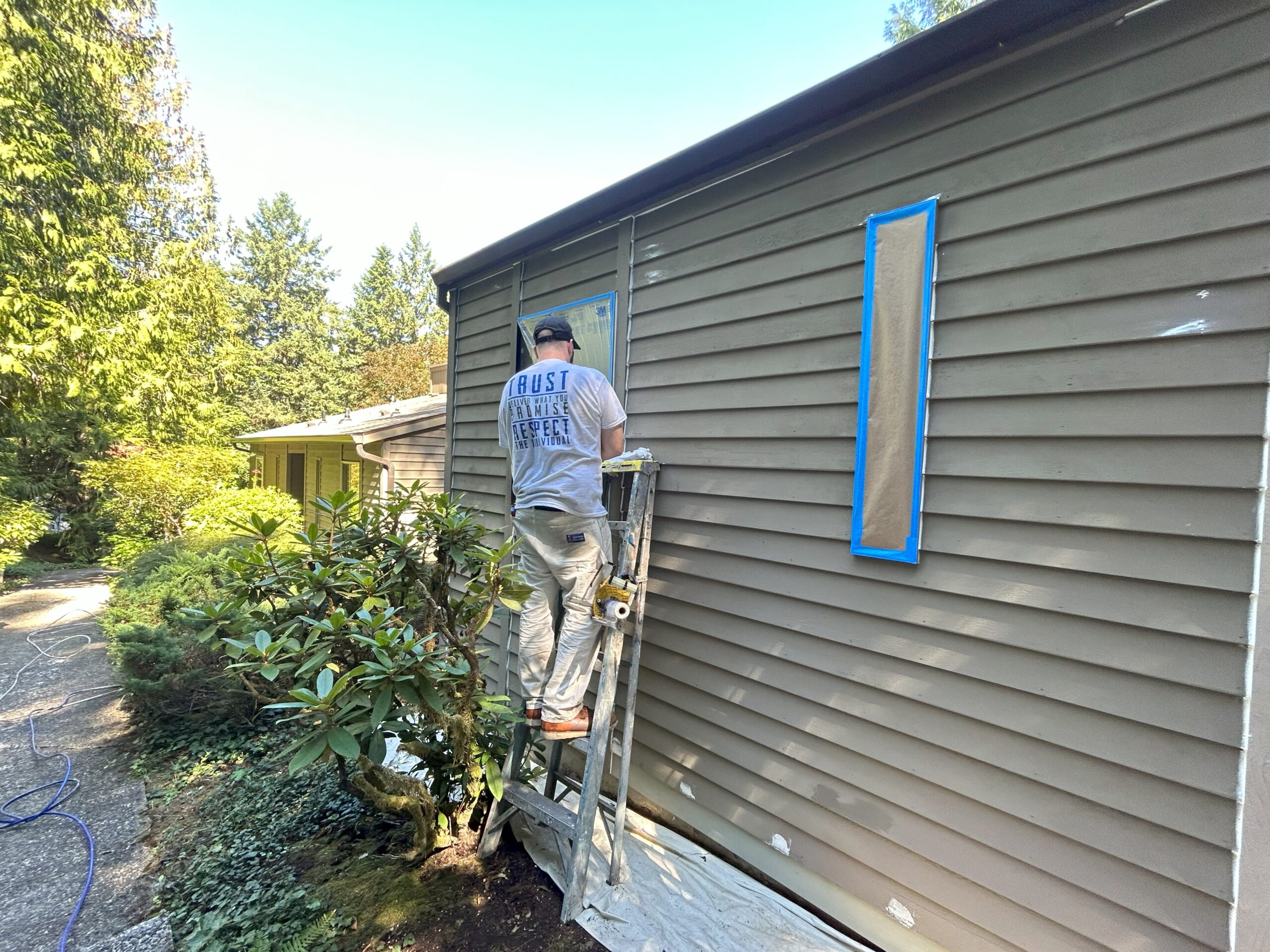 A man applying exterior paint to the siding of a Portland home, creating a fresh feel.