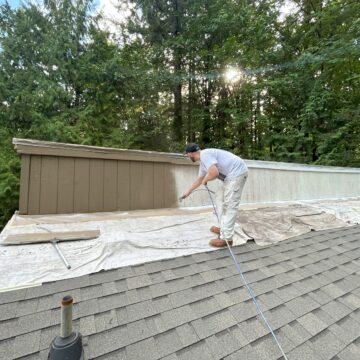 A man using fresh exterior paint to revitalize a roof in the woods near Portland.