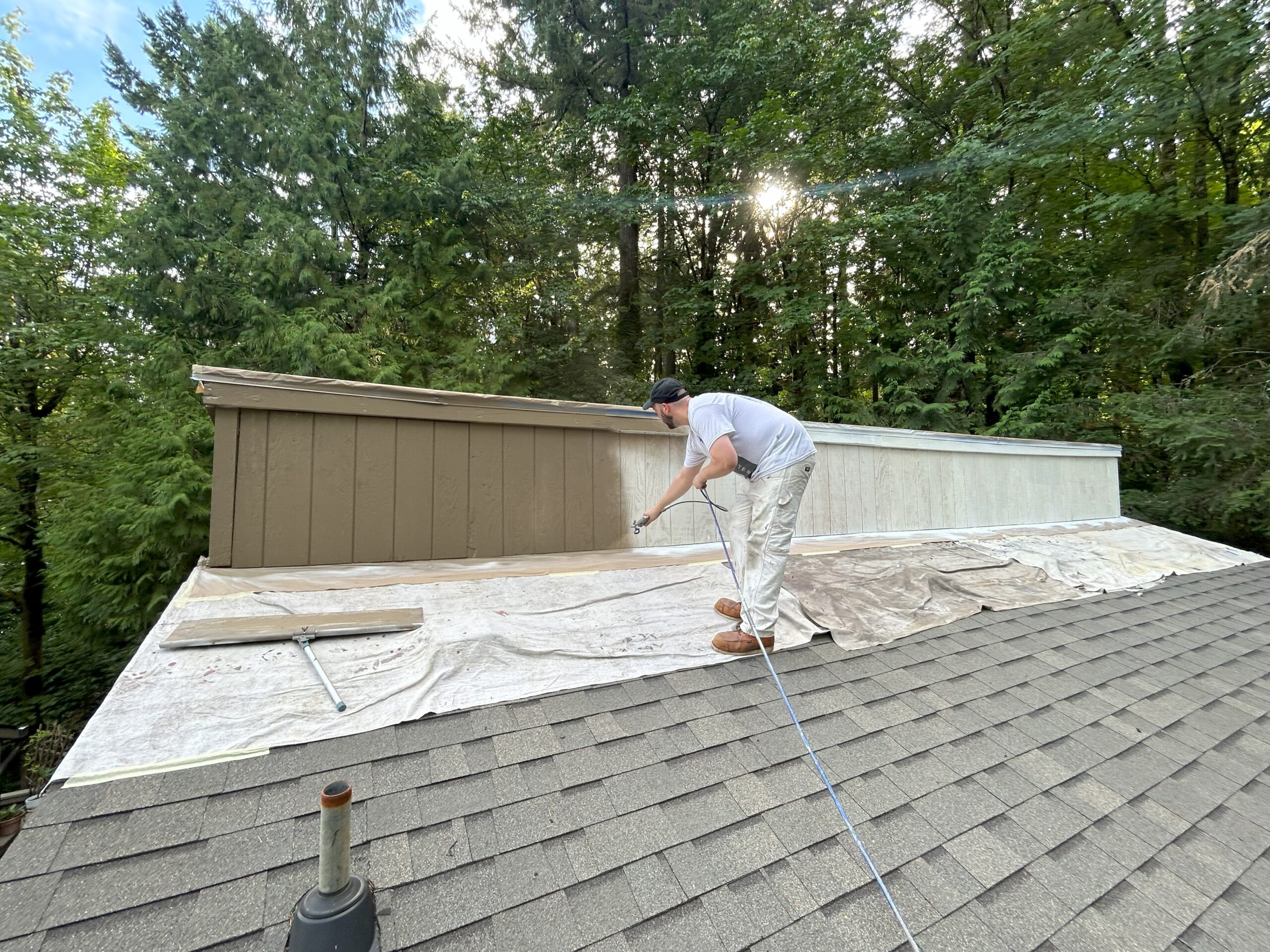 A man using fresh exterior paint to revitalize a roof in the woods near Portland.